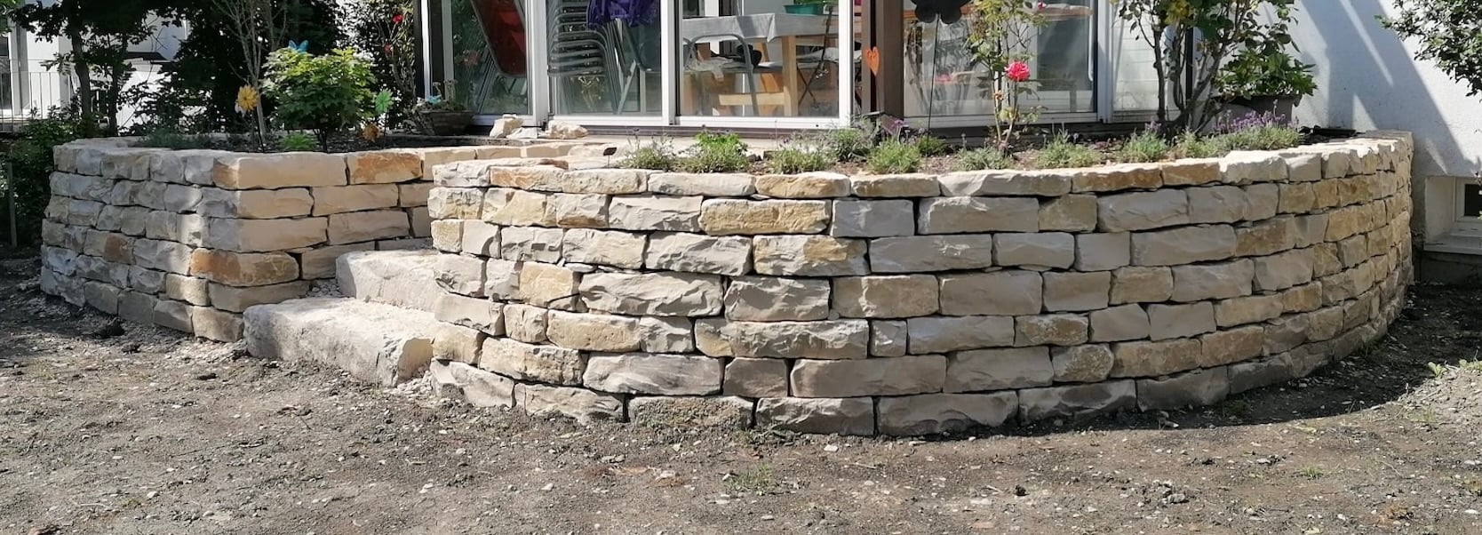 Mur en pierre sèche en courbe avec terrasse aménagée